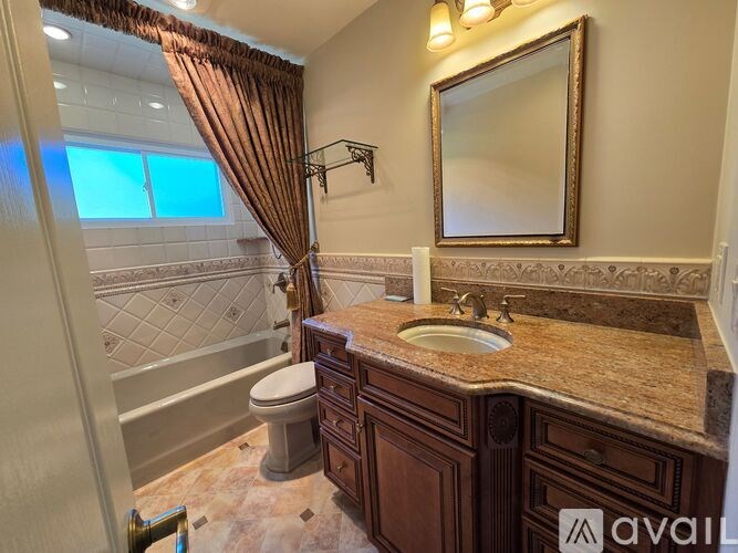 A bathroom with a brown counter top and a large mirror.
