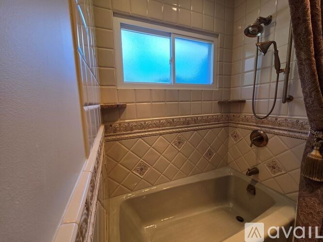 A bathroom with a tub, shower, and a window.