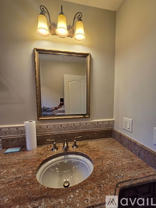 A bathroom with a granite countertop and a large mirror above the sink.