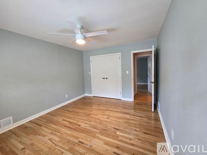 A room with a ceiling fan and wooden flooring.