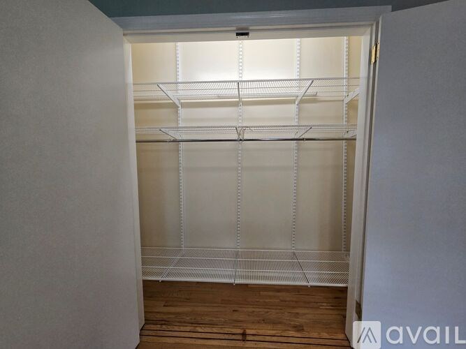 A white walk-in closet with shelves and a wooden floor.