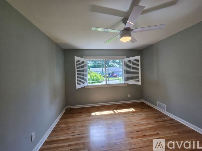 A room with a ceiling fan and a window with blinds.