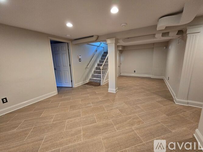 A spacious room with a tiled floor and a staircase leading to another level.
