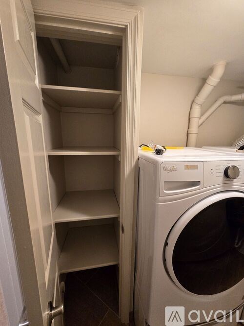 A white dryer is in a small laundry room.