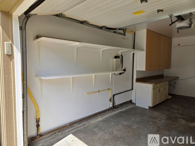 A room with a white wall and a white fridge with a yellow pipe.