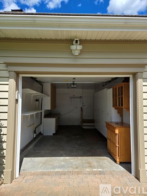 A garage with a white refrigerator and wooden cabinets.