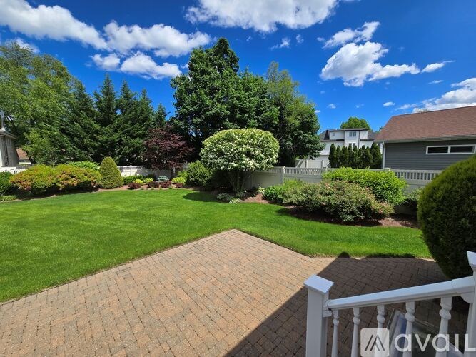 A well-maintained garden with a white fence and a variety of plants.