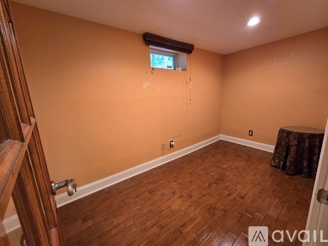 A room with wooden flooring and a window with a view of a tree.