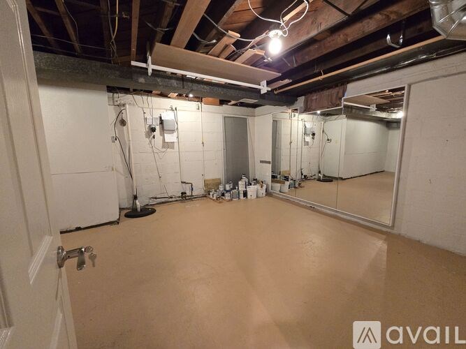 A spacious empty room with a door on the left and a mirror on the right.