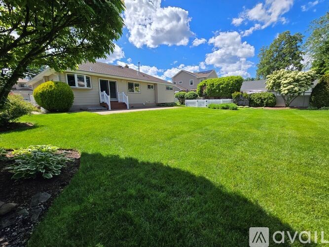 A well-maintained lawn in front of a house with a clear blue sky above.
