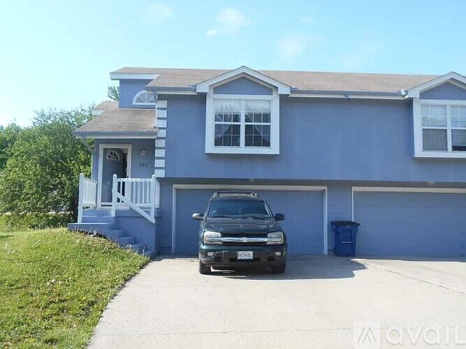 A house with a blue exterior and a black truck parked in front.