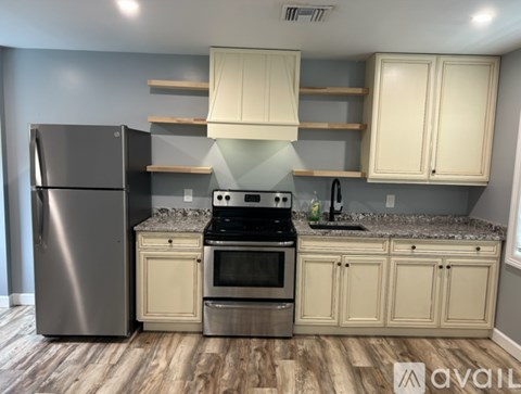 A kitchen with a stainless steel refrigerator, a stainless steel oven, and white cabinets.