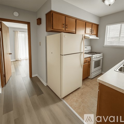 A kitchen with a white refrigerator, wooden cabinets, and a stove top oven.