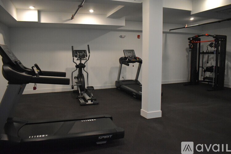 A gym with a treadmill, elliptical trainer and a weight machine.