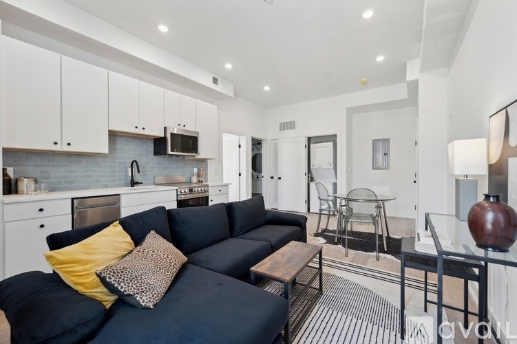 A modern living room with a black sofa and a glass coffee table.