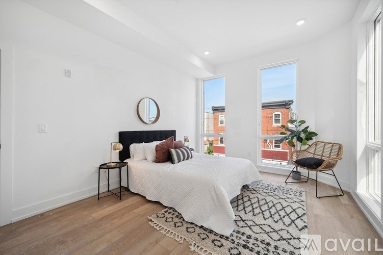 A bedroom with a large bed, a round mirror, and a chair.