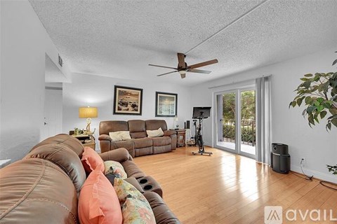 A living room with a brown leather couch and a ceiling fan.