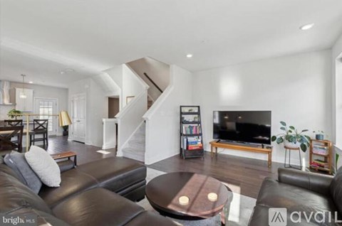 A living room with a black leather couch and a wooden coffee table.