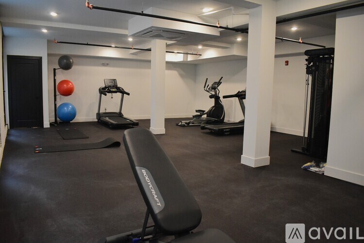 A gym with a variety of equipment including a treadmill, exercise balls, and a bench.