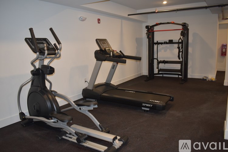 A gym room with a treadmill, elliptical trainer and a stationary bike.