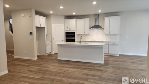 A modern kitchen with white cabinets and a wooden floor.