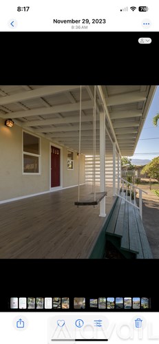 A wooden deck with a bench and a red door.