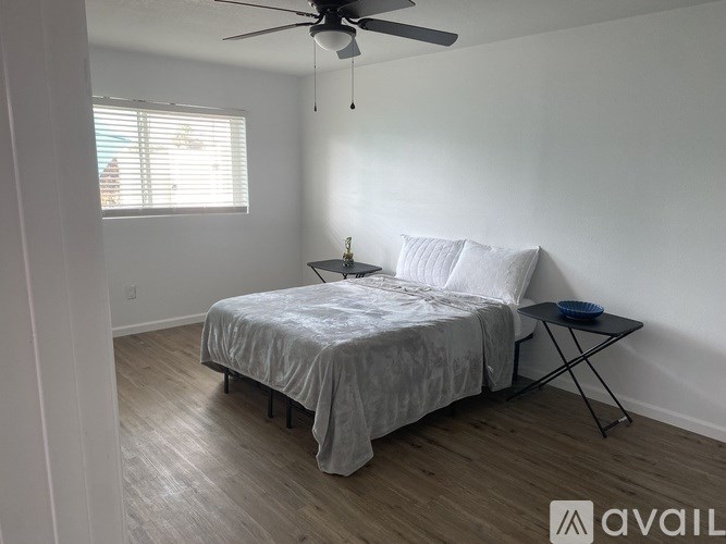 A bedroom with a bed, a ceiling fan, and a small table with a bowl on it.
