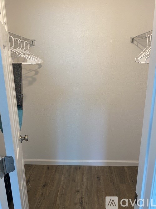 A white door with a silver handle and a white wall with a coat rack.