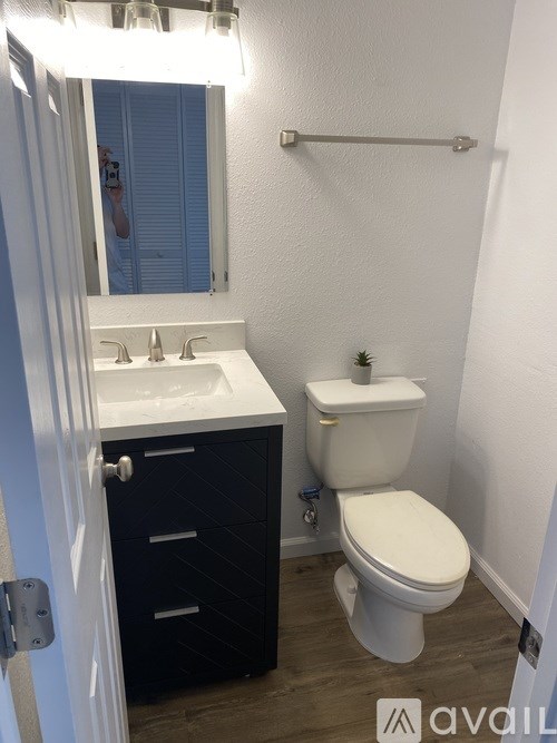 A bathroom with a toilet, sink, and mirror.
