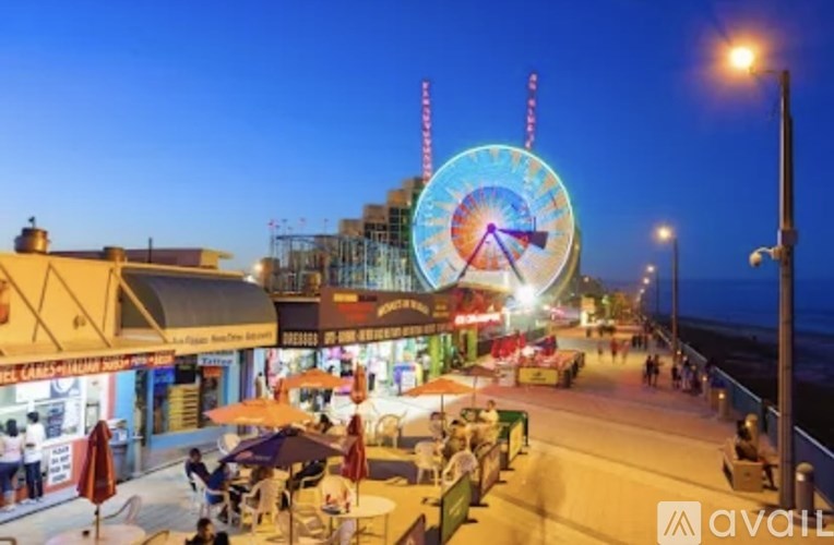 A Ferris wheel is lit up at night in a crowded plaza.