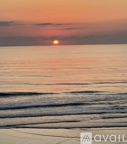 A sunset over the ocean with the sun just above the horizon.