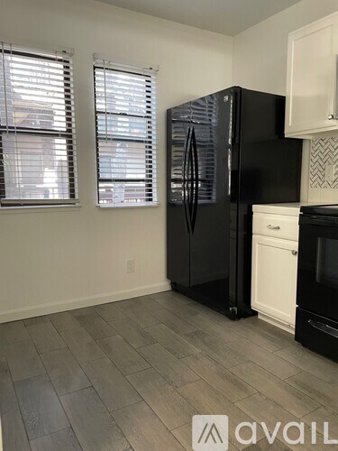 A kitchen with a black refrigerator and a white oven.