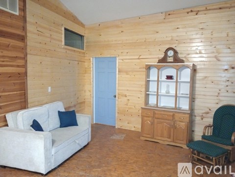 A living room with a white couch, a wooden cabinet, and a green chair.