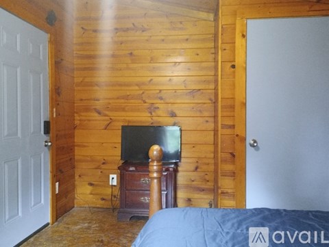 A bedroom with a bed, dresser and a television.
