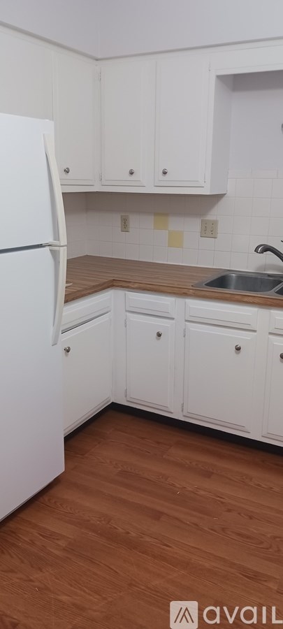 A kitchen with white cabinets and a white refrigerator.