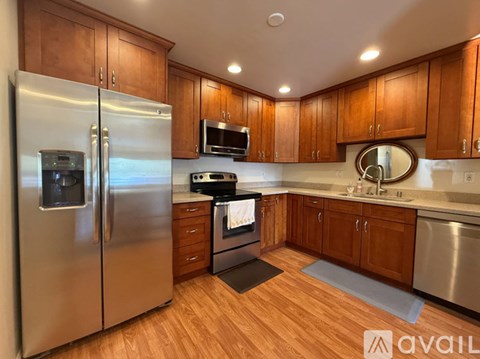 A kitchen with wooden cabinets and a stainless steel refrigerator.