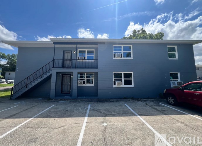 A grey building with a red car parked in front.