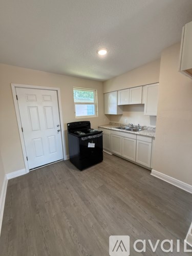 A kitchen area with a black fridge and a white door.