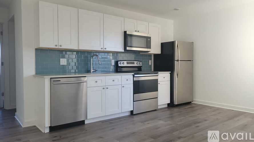 A kitchen with white cabinets and a black fridge.