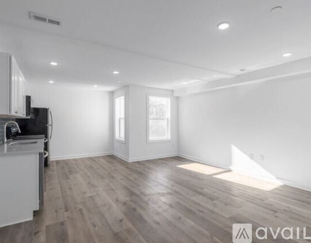 A spacious living room with wooden flooring and white walls.