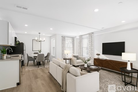 A spacious living room with wooden flooring and white walls.