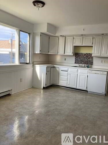 A kitchen with white cabinets and appliances is available for rent.