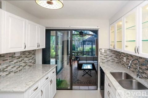 A kitchen with white cabinets and a marble countertop.