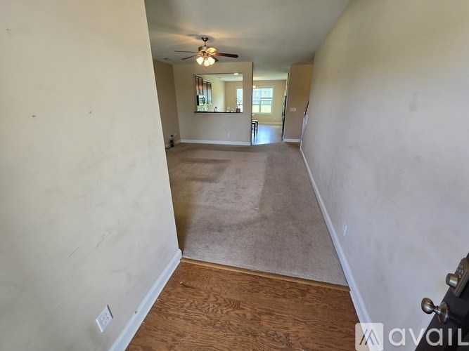 A room with a ceiling fan and a door leading to another room.