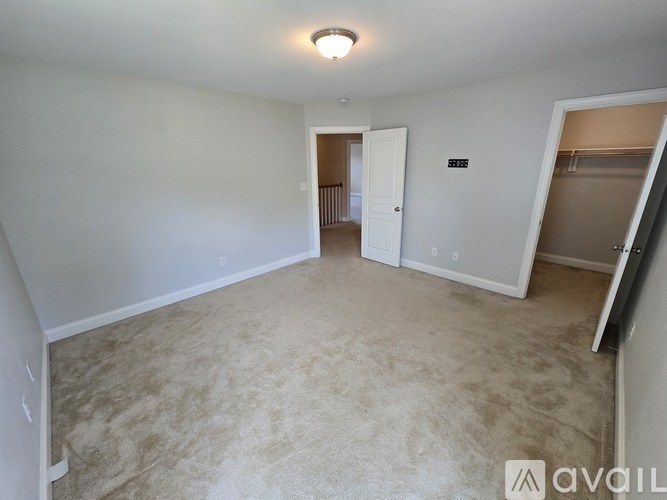 A spacious room with a carpeted floor and a doorway leading to another room.