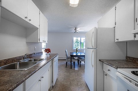 A kitchen with white cabinets and a table with chairs.