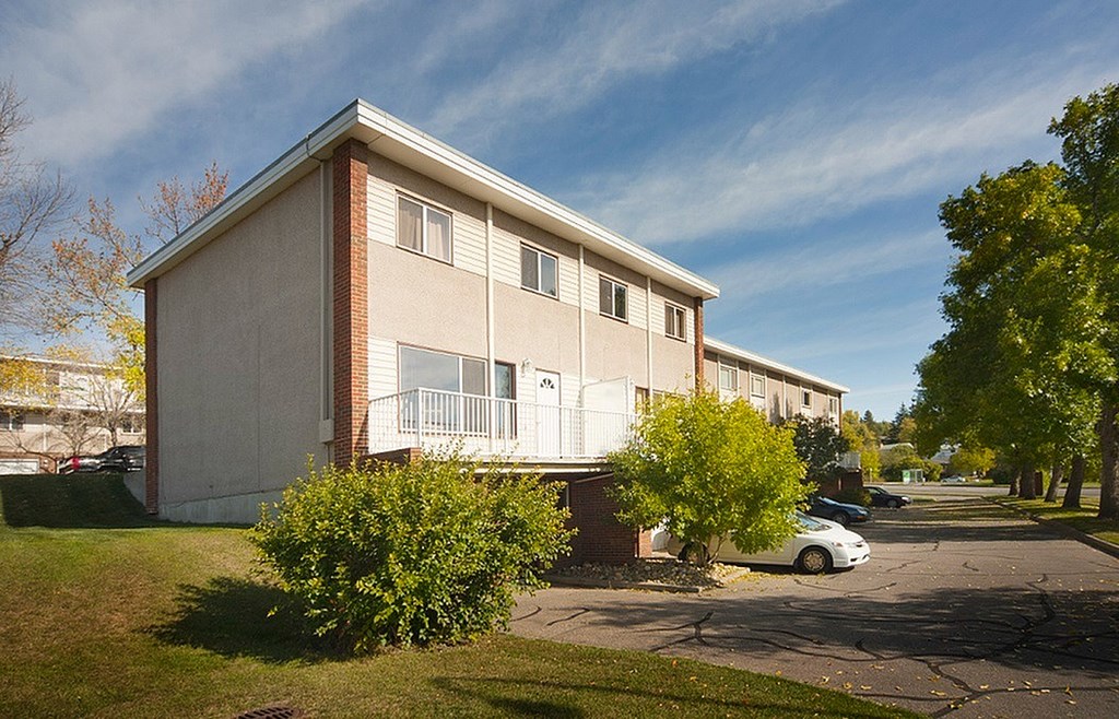 A small apartment building with a car parked in front.
