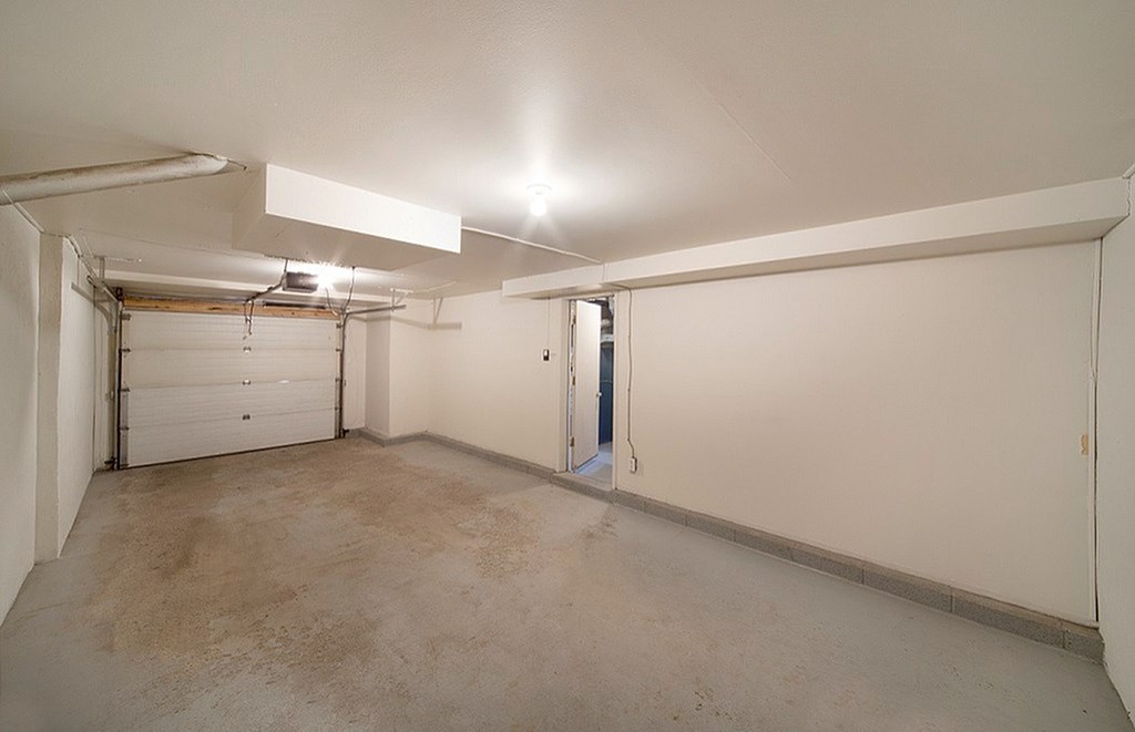 A large empty garage with a white wall and a door.