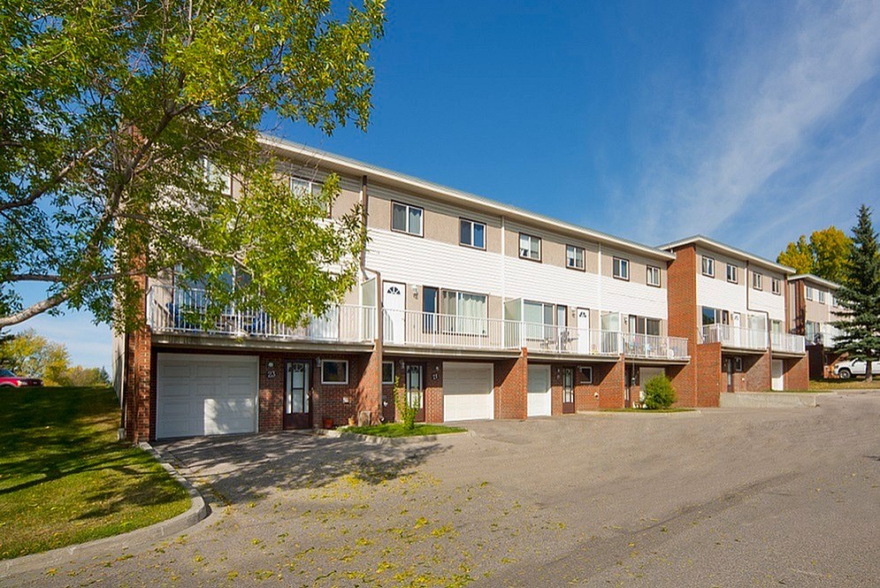 A large apartment building with a parking lot in front.