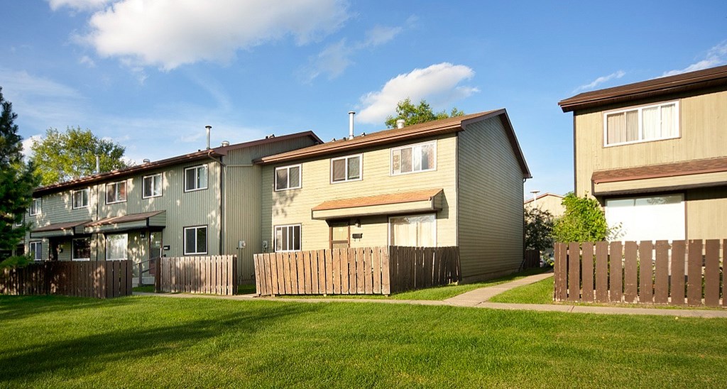A row of houses with a green lawn in front.